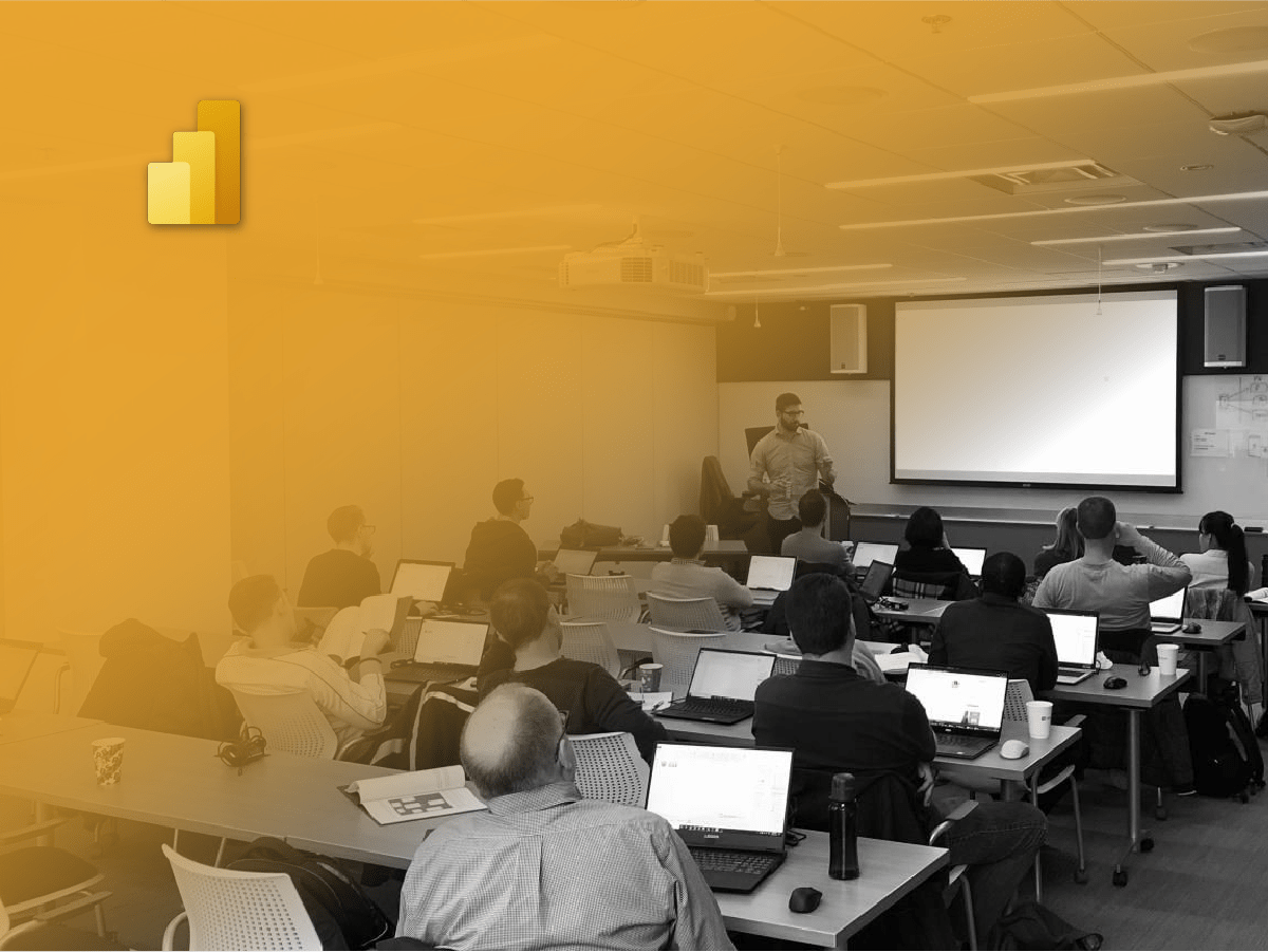 A group of individuals engaged in a Business Intelligence Solutions workshop, attentively working on laptops at tables.