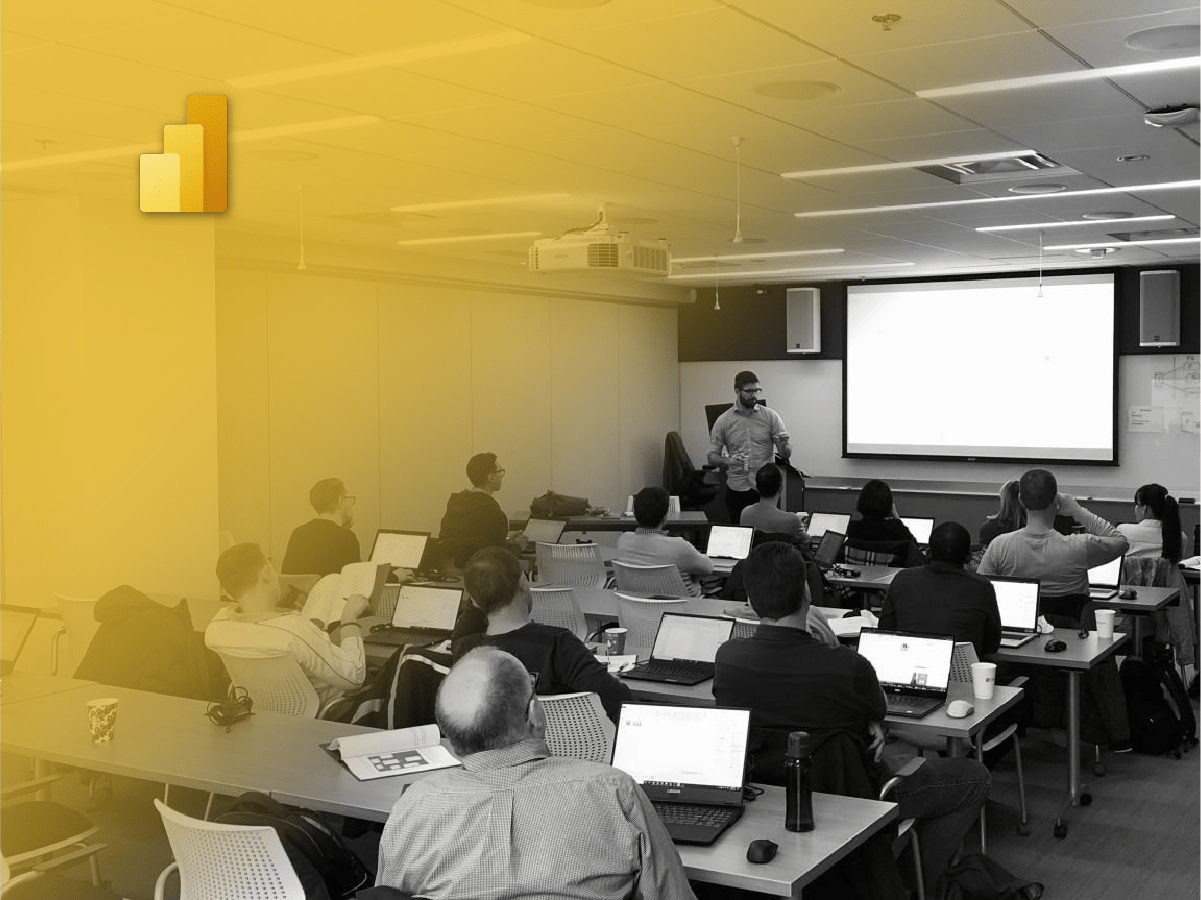 A group of individuals engaged in a Business Intelligence Solutions workshop, attentively working on laptops at tables.